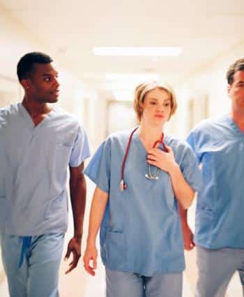Nurses Walking Through A Hospital Hallway Stock Photo